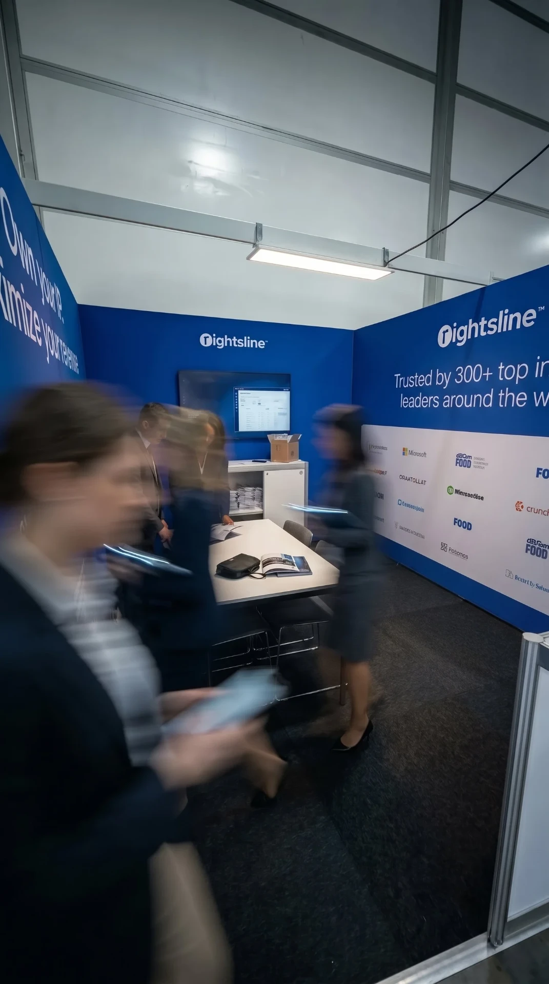 The Rightsline stand at IBC, Amsterdam — blue meeting room with Rightsline branding, demo screen and visitors
